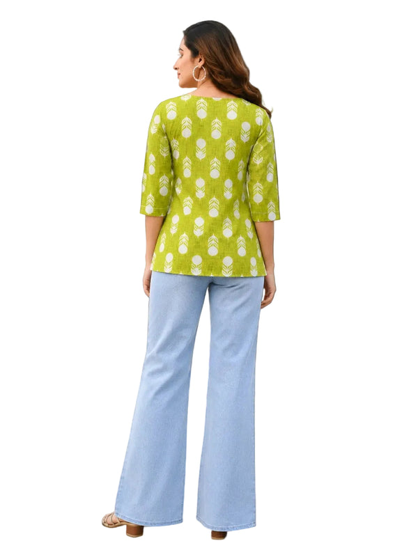 A woman is shown from the back wearing a lime green kurta with a white floral print and light blue wide-leg pants, standing on a checkered floor against a light-colored wall.