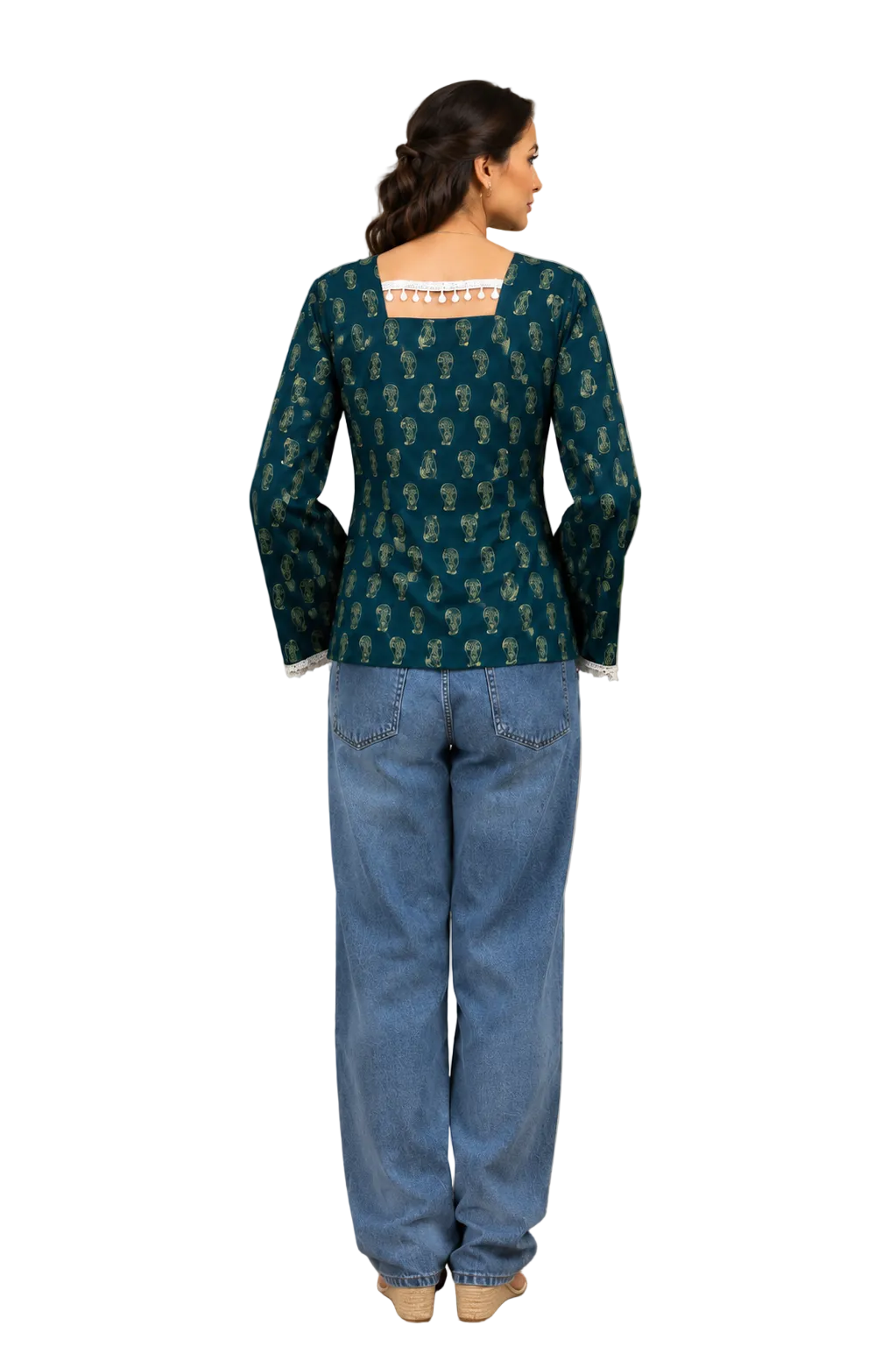 A woman shown from the back wearing a teal green printed kurta with a square neckline and long bell sleeves, paired with wide-leg blue jeans, in a warm-toned indoor setting.