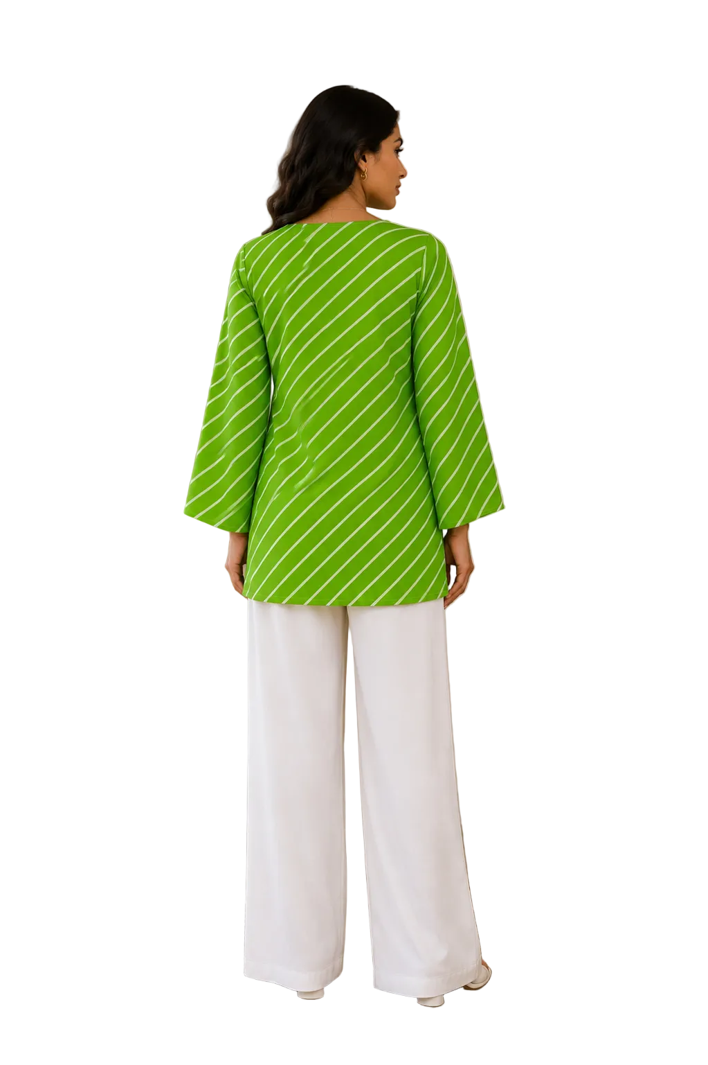 A woman stands with her back to the camera wearing a bright lime green top with thin white diagonal stripes and white wide-leg pants in a warm, neutral-toned indoor setting.