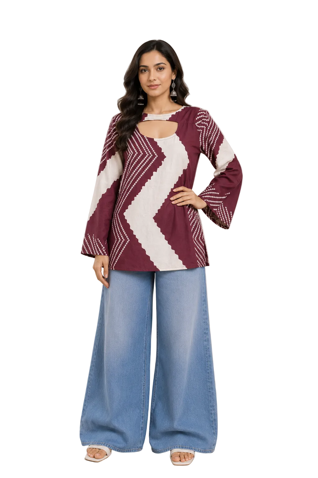 A woman modeling a long-sleeve top with a deep V-neckline and a burgundy and white geometric pattern, paired with wide-leg blue jeans in a warm, neutral-toned indoor setting.