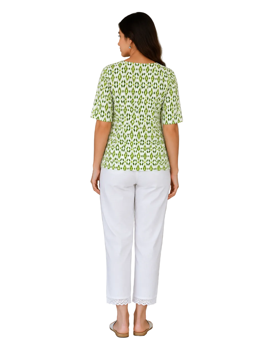 A woman is shown from the back wearing a light green and white patterned short-sleeve top and white cropped pants with lace trim, standing in an indoor setting next to a potted plant and a wooden door.