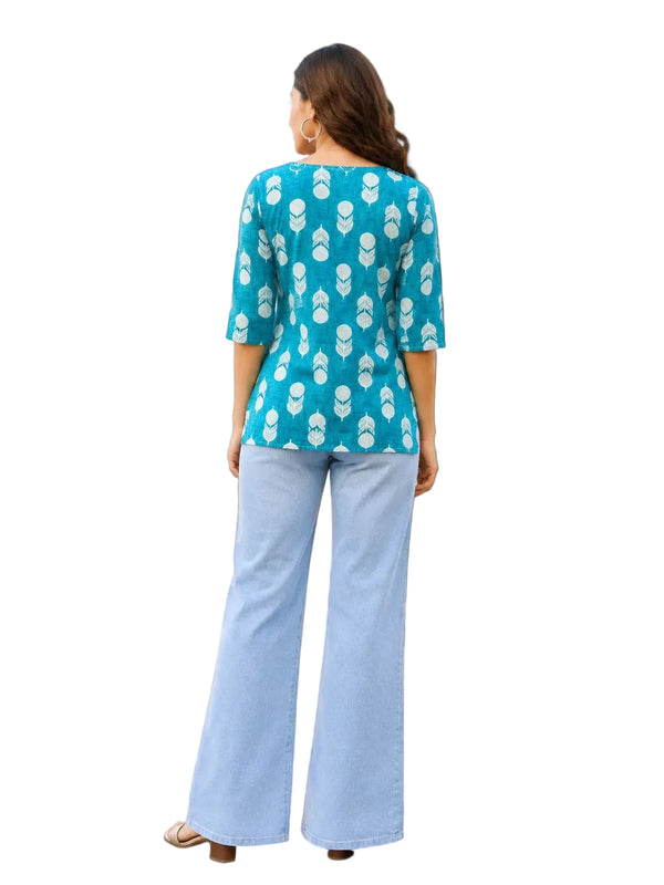 A woman viewed from behind wearing a turquoise blue and white patterned kurta with three-quarter sleeves and light blue wide-leg jeans, standing on a checkered floor against a light-colored wall.